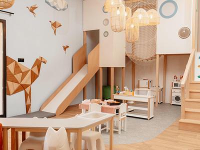 Area giochi per bambini con giocattoli di legno, scivolo e decorazioni murali nell'interno di un hotel.