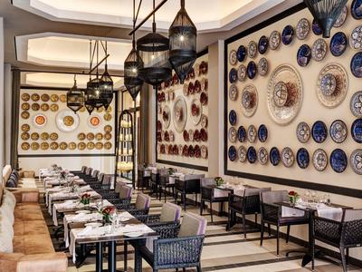 Ristorante con tavoli lunghi e pareti decorate con piatti decorativi blu-bianco e marroni.