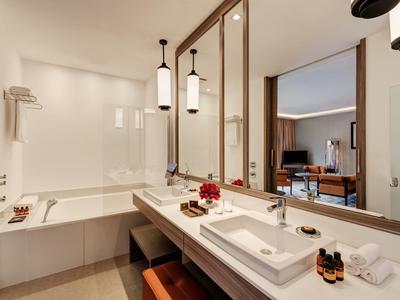 Bagno moderno in hotel con vasca, lavabo, grandi specchi e illuminazione indiretta.