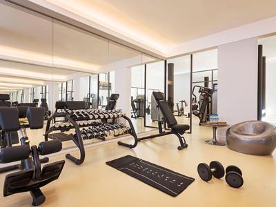 Palestra moderna con manubri, attrezzi per allenamento e pareti a specchio in una stanza luminosa