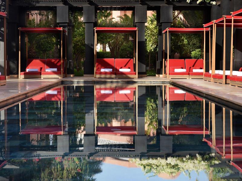 Area piscina moderna con posti a sedere e piante verdi al tramonto.