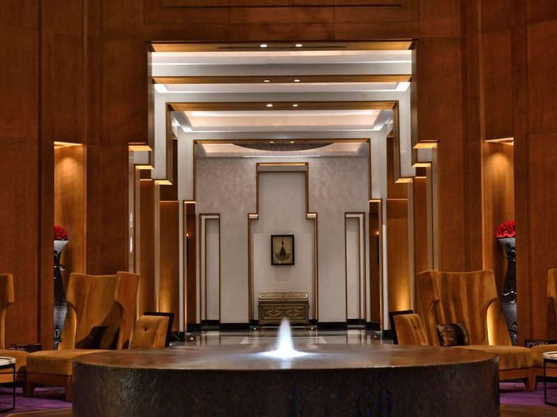 Elegante hall dell'hotel con fontana, soffitto alto e pareti in legno.