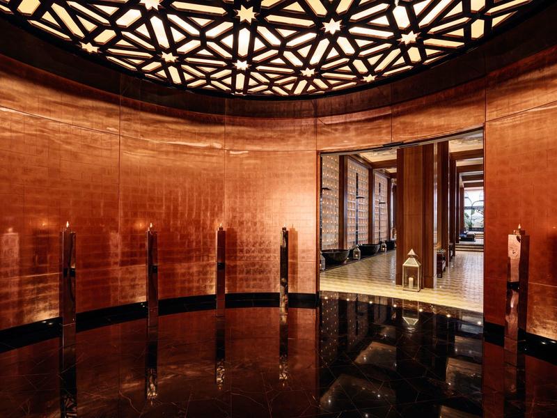 Stanza rotonda moderna con pareti in legno e specchi e illuminazione geometrica sul soffitto.