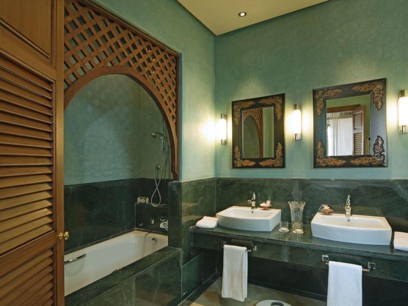 Nowoczesna łazienka z podwójnymi umywalkami, wanną i lustrami w zielonych i brązowych odcieniach.