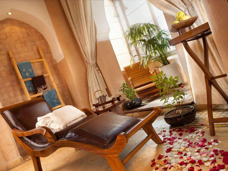 Przytulne wnętrze z drewnianym leżakiem, roślinami i płatkami kwiatów na podłodze w spa.