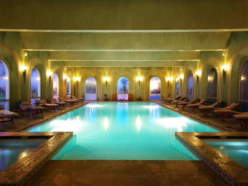 Duży kryty basen z ciepłym oświetleniem i leżakami w luksusowym hotelu.