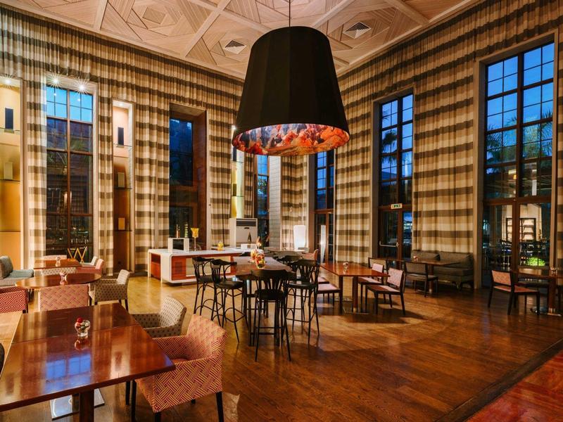 Elegancka restauracja hotelowa z drewnianą podłogą, dużymi oknami i nowoczesnym oświetleniem.