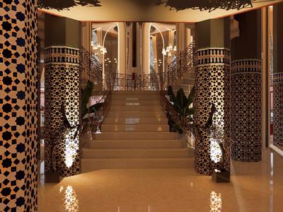 Eleganter Hotelflur mit gemusterten Säulen und Treppe im Hintergrund.