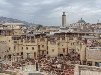 Traditionelle Gerberei mit ledrigen Fässern inmitten einer Stadt mit historischen Gebäuden.