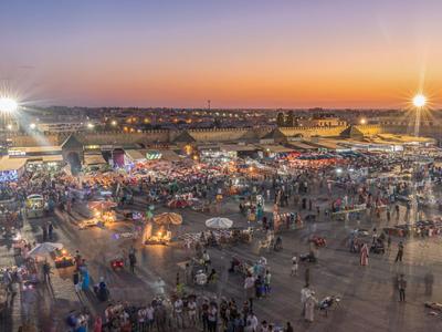 Großer belebter Markt bei Sonnenuntergang mit vielen Leuten und Ständen.