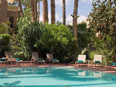 Zwembad met ligstoelen en palmbomen in een tropische hotelomgeving