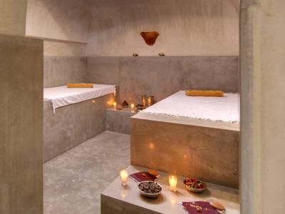 Minimalistische spa-ruimte met twee ligbedden, kaarsen en gedimd licht.