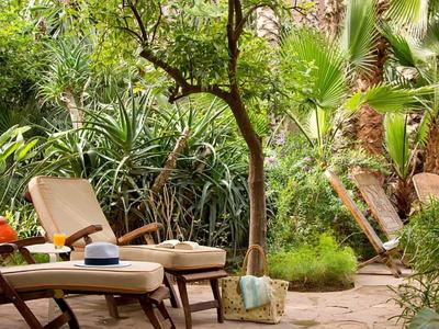 Comfortabele tuinligstoelen in de schaduw omringd door weelderig tropisch groen.