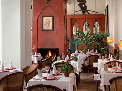 Gezellig restaurant met witte tafelkleden, open haard en warm licht.