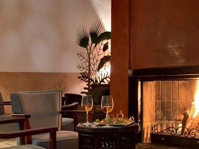 Gezellige zithoek met open haard en wijn in warm licht.