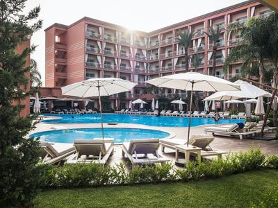 Buitenzwembad met ligstoelen en parasols voor een meerlaagse hotelgebouw