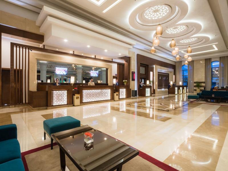 Elegante hotel lobby met moderne verlichting, receptie en zitgedeeltes.