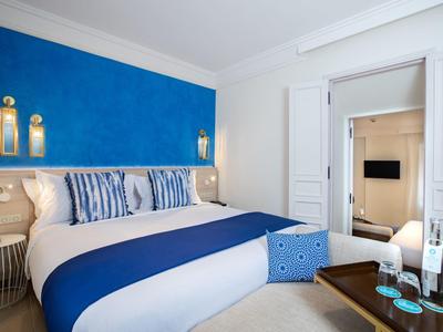 Modernes Schlafzimmer mit großem Bett, blau-weißer Bettwäsche und stilvollen Dekorationen.