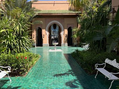 Un cortile tropicale con piscina d'acqua turchese, palme e panchine bianche.
