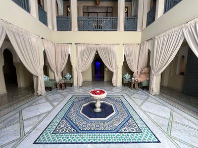 Cortile con motivo di piastrelle blu, fontana al centro e tende bianche sulle colonne.