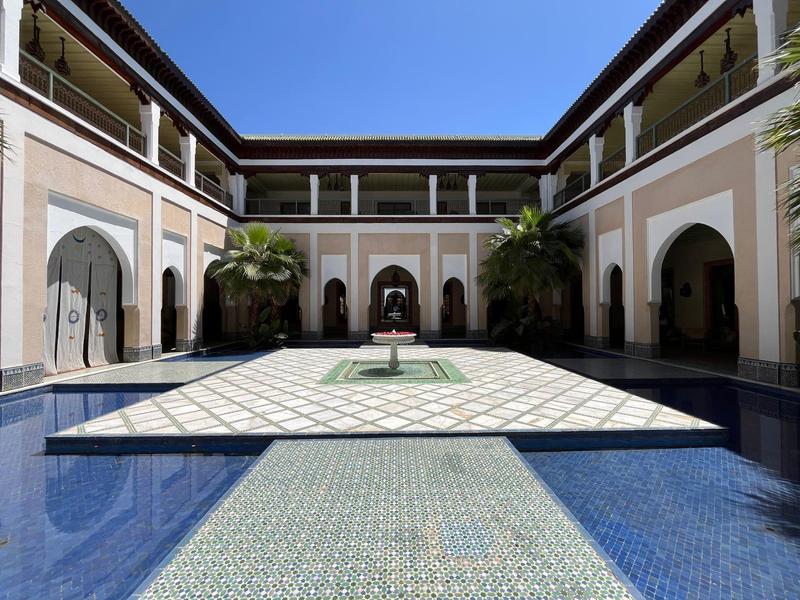 Cortile di un hotel con bacino d'acqua, fontana e colonnati sotto un cielo limpido