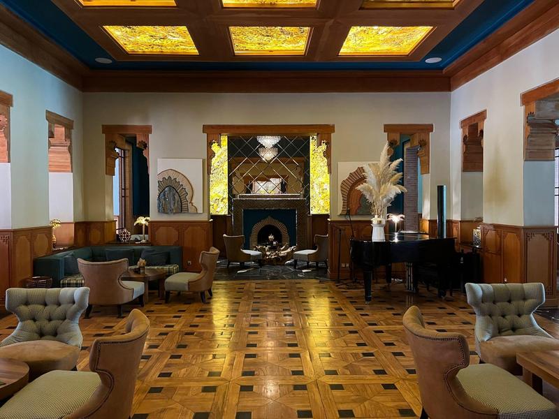 Elegante lounge d'hotel con pavimento in legno, poltrone accoglienti e pianoforte vicino al camino.