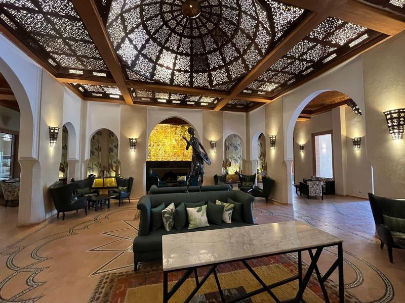 Elegante hall di un hotel con finestra a soffitto artistica, aree salotto e illuminazione calda.