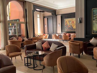 Przytulny salon hotelowy z brązowymi fotelami i stolikami w jasnym otoczeniu.