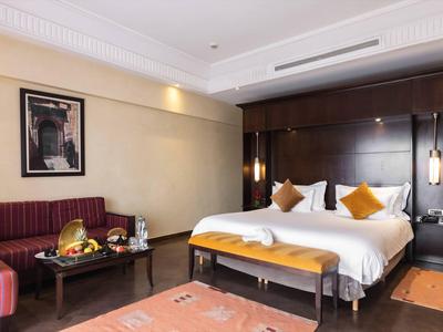 Nowoczesny pokój hotelowy z podwójnym łóżkiem, sofą, ławką i stylowym oświetleniem.