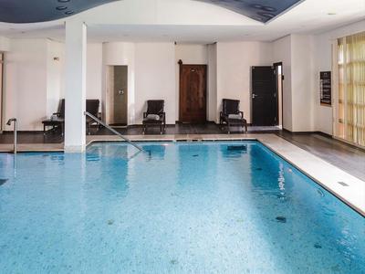 Basen kryty z niebieską wodą i wygodnymi leżakami w jasnym pomieszczeniu