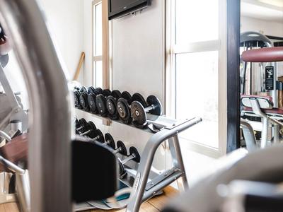 Jasna siłownia z hantlami, telewizorem i dużymi oknami.