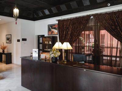 Recepcja hotelowa z ciemnym drewnianym konturem, lampami i widokiem na zasłony oraz korytarz.