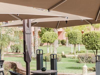 Taras z stolikami, krzesłami i parasolami w zielonym ogrodzie