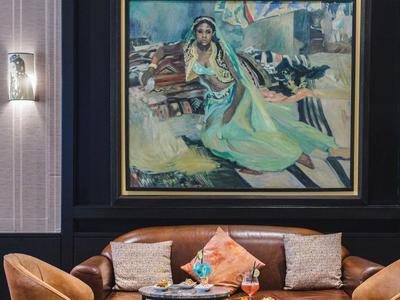 Przytulny kącik wypoczynkowy z brązową sofą, dwoma fotelami i dużym obrazem na ścianie