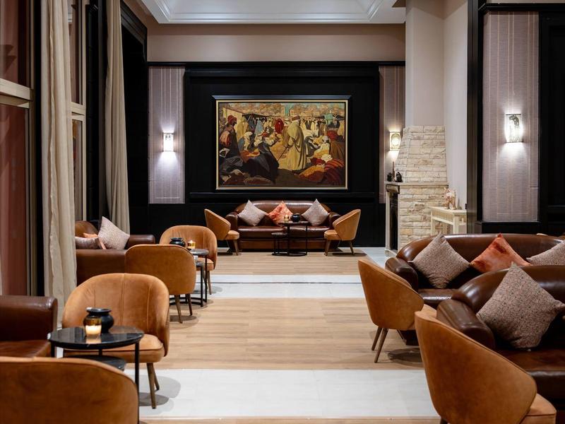 Espace lounge élégant d'hôtel avec fauteuils confortables, sol en bois et décoration murale élégante.