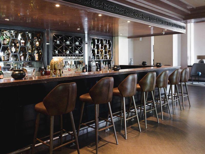 Espace bar d'hôtel moderne avec tabourets en cuir et bar bien éclairée