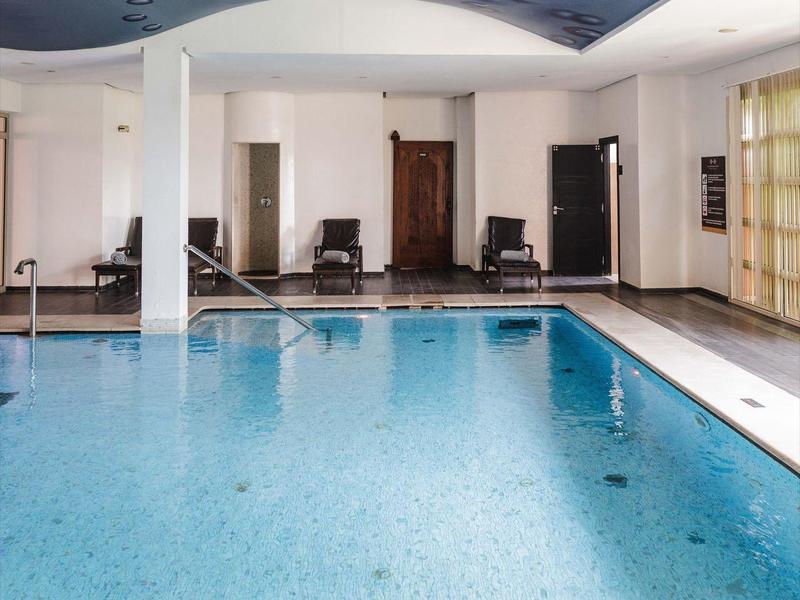 Piscine intérieure avec eau bleue et motif de gouttes d'eau au plafond dans une pièce lumineuse