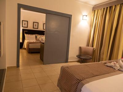 Zwei benachbarte Hotelzimmer mit Betten, Gardinen und Stuhl beleuchtet.