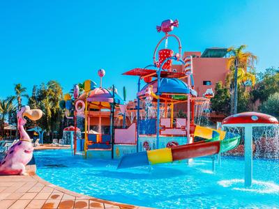 Bunter Wasserspielplatz mit Rutschen und Wasserspritzern in einem Hotelpool unter klarem Himmel.