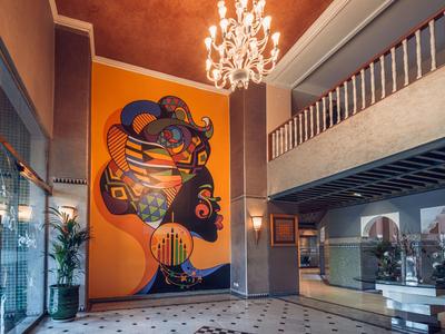 Hotel-Lobby mit moderner Kunst an der Wand, großem Kronleuchter und offenen Bereichen.