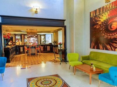 Helliges Hotellobby mit bunten Stühlen, Teppich und modernem Kunstwerk an der Wand.