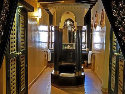 Elegantně zdobená hotelová chodba s tmavými závěsy a kulatým centrálním posezením.