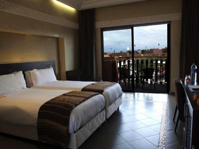 Hotelzimmer mit zwei Betten, Terrassentür und Blick auf verrauschte Außenanlage.