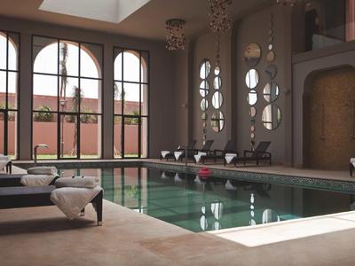 Innenpool mit hohen Fenstern, Liegestühlen und elegantem, ruhigem Ambiente für Erholung.