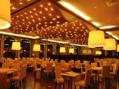 Elegantes Hotelrestaurant mit warmem Licht, zahlreichen Tischen und bequemen Stühlen.