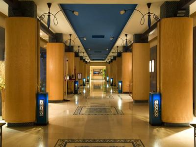 Großer, eleganter Hotelflur mit dicken Säulen, warmem Licht und Teppichläufern.