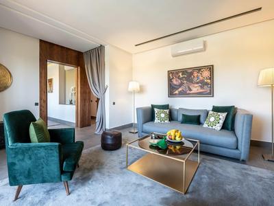 Soggiorno moderno con divano, poltrona e accenti dorati in una stanza d'hotel.