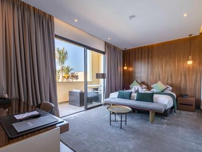 Camera d'hotel moderna con letto grande, pannelli in legno e accesso alla terrazza.