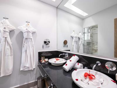 Bagno moderno con doppi lavandini, accappatoi bianchi e grande specchio.