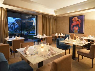 Ristorante elegante in hotel con tavoli apparecchiati, sedie e illuminazione serale.